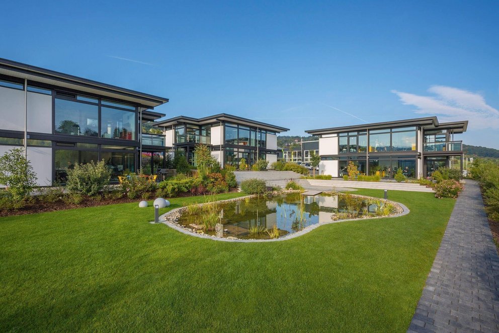 Architektenhaus in einer grünen Umgebung mit Teich und Weg