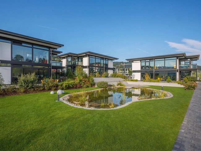 Architektenhaus in einer grünen Umgebung mit Teich und Weg