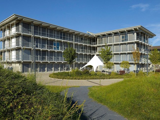 Bürogebäude HUF mit Grünflächen und blauer Himmel