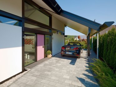Eingang eines modernen Architektenhauses mit Carport und Garten