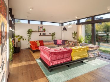 Modernes Designhaus mit Flachdach und farbenfrohem Interieur Helles Wohnzimmer mit buntem Sofa und Pflanzen im modernen Designhaus
