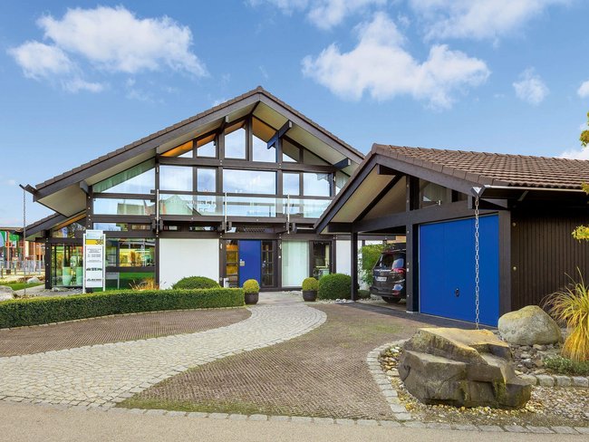 Architektonisches Design eines Hauses mit grünem Garten und Garageneinfahrt