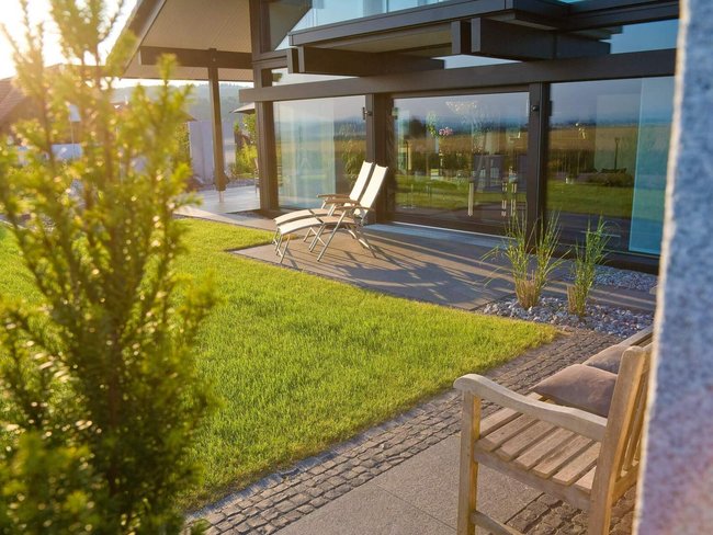 Helles Architektenhaus mit Garten und Liegen in der Abendsonne