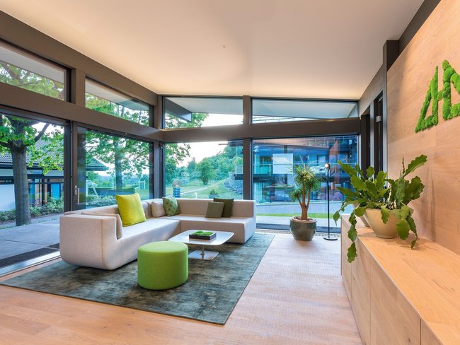 Moderne Wohnlandschaft mit grünen Akzenten Helles Wohnzimmer mit eleganter Couch und Pflanzen