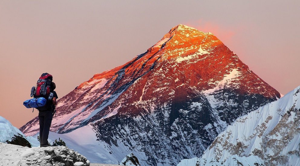 Ein Wanderer schaut auf den erleuchteten Himalaya-Gipfel