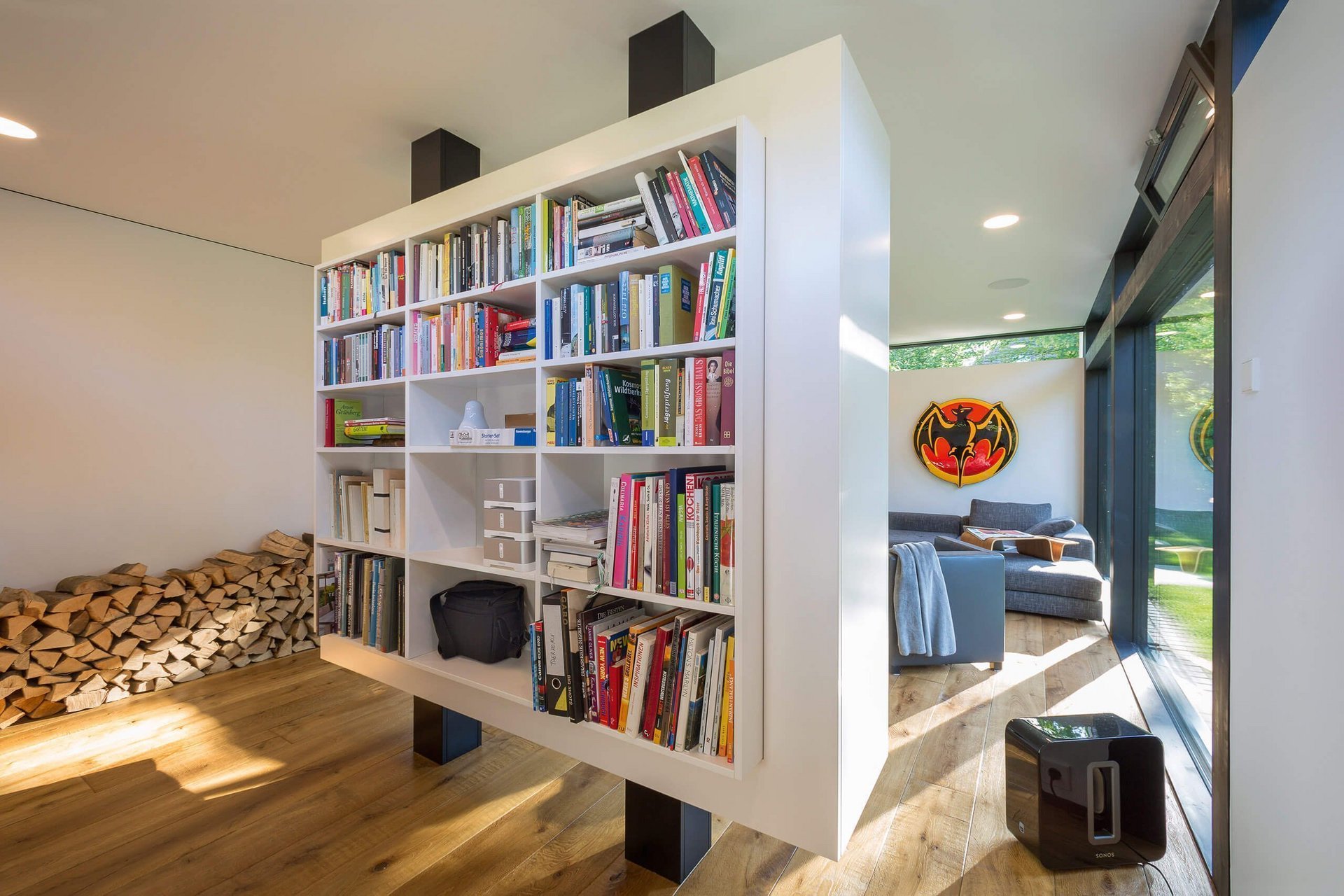Moderne offene Wohnraum mit schwebendem Bücherregal Interior eines modernen Wohnraums mit Bücherregal und Holzstapel
