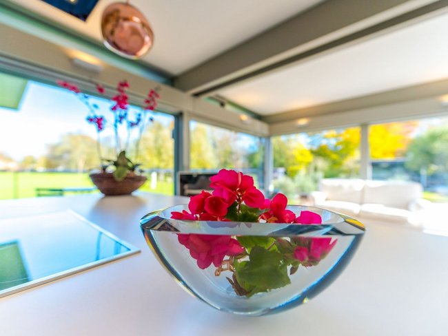 Eleganter HUF Anbau mit stilvollem Wohnraum Blumenarrangement im modernen HUF Anbau mit Glasflächen