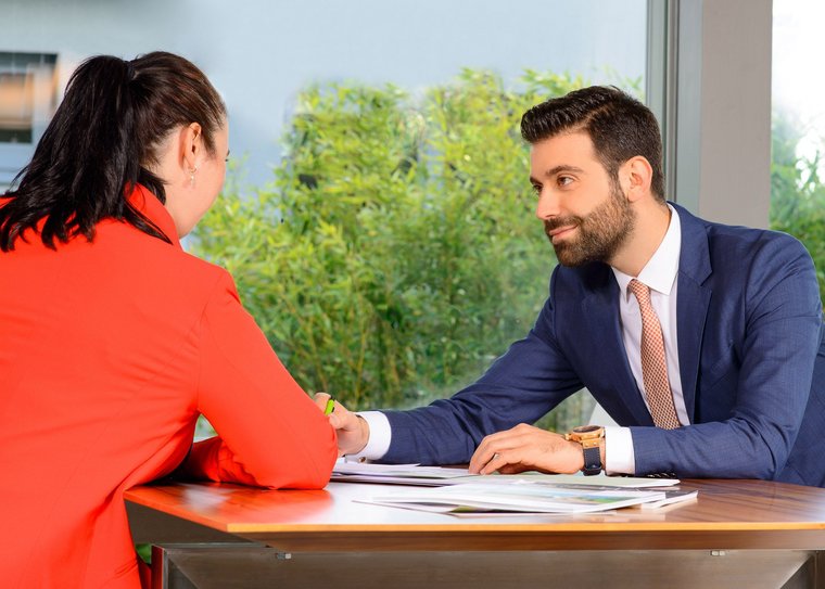 Geschäftliches Gespräch zwischen zwei Personen Zwei Personen im Gespräch an einem Tisch mit Dokumenten