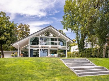 Architektenhaus am Wasser mit großflächigen Fenstern und gepflegtem Garten
