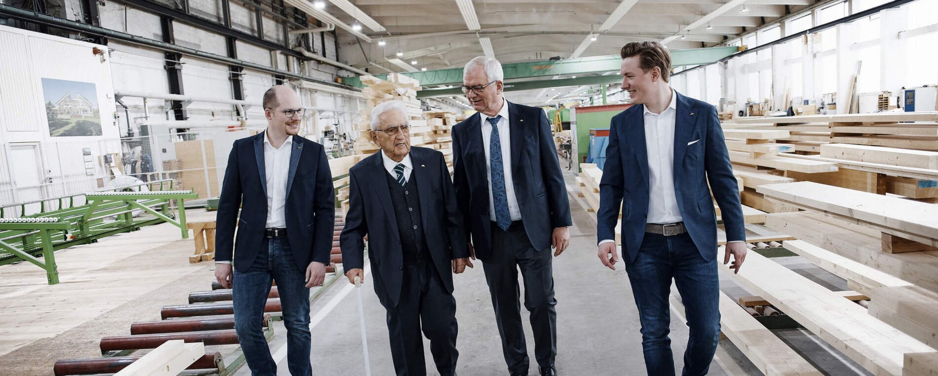 Besuch in einer Holzverarbeitungshalle Vier Männer gehen durch eine Holzverarbeitungshalle