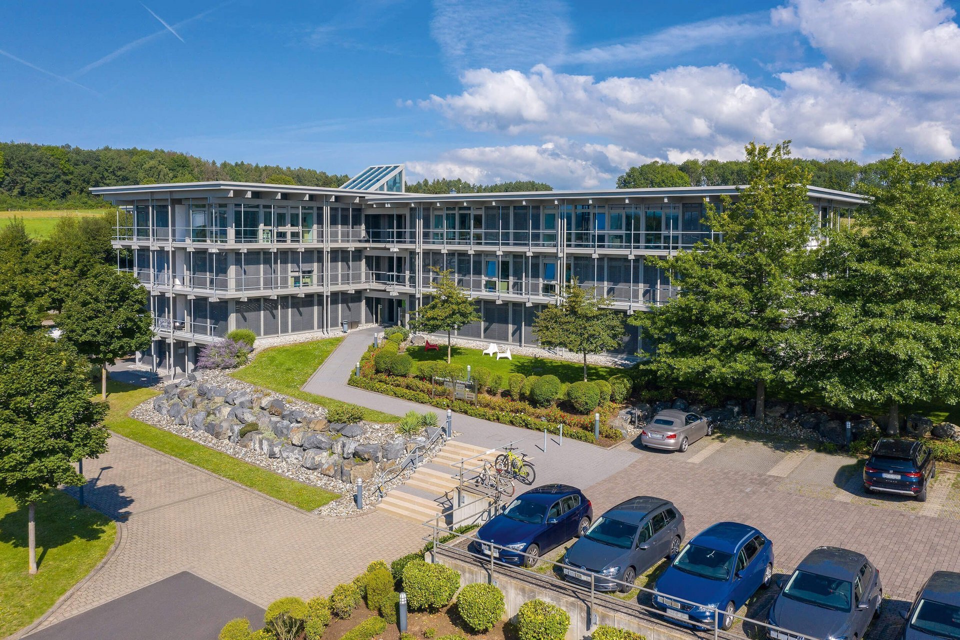 Moderne Architektur des Bürogebäudes umgeben von Bäumen und Autos