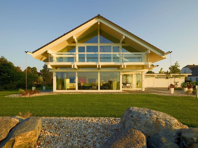 Fachwerkhaus HUF HAUS ART 4 in der Abendsonne Moderne Architektur eines Fachwerkhauses mit großen Fenstern und Garten