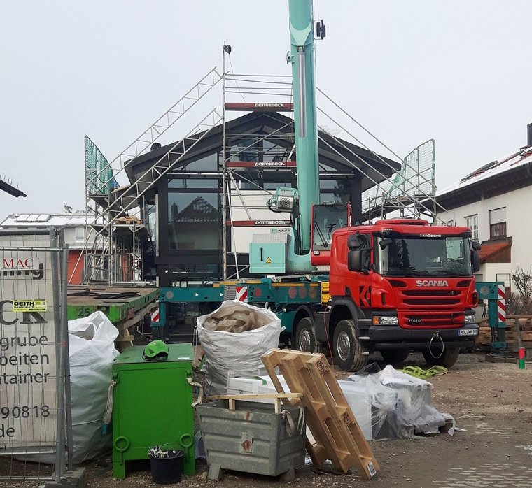 Kran hebt Materialien auf einer Baustelle mit Aufbau eines Hauses