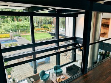Blick auf ein elegantes Wohnzimmer mit großen Fenstern und Gartenansicht