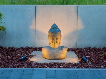 Gemütliche Buddha-Skulptur aus Stein in einem japanischen Garten
