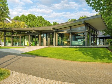 Ein modernes Gebäude mit Glas und Grünflächen in der Nähe