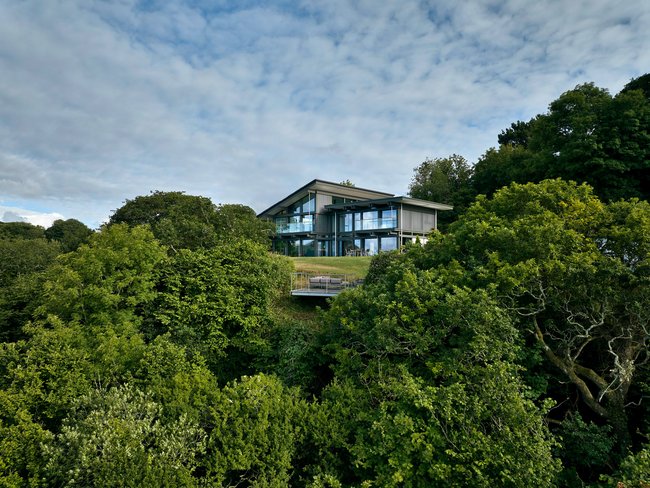 HUF Haus am Meer – Modernes Designhaus in der Natur Modernes Haus umgeben von Bäumen, mit Glasfassade und schöner Aussicht