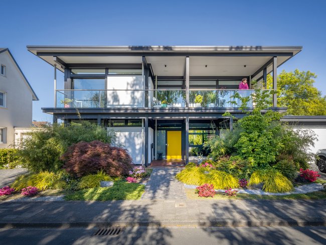Modernes Designhaus mit Flachdach und Gartenanlagen Stilvolles modernes Haus mit Flachdach und bunten Blumen im Garten
