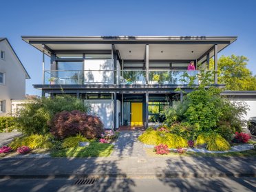 Modernes Designhaus mit Flachdach und Gartenanlagen Stilvolles modernes Haus mit Flachdach und bunten Blumen im Garten