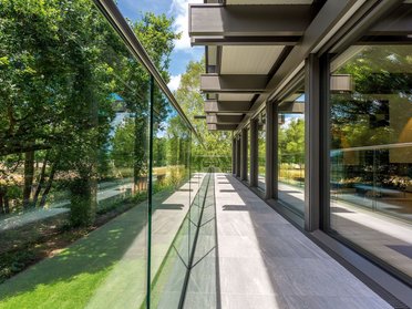 Futuristischer Balkon mit Glasgeländer und grüner Umgebung