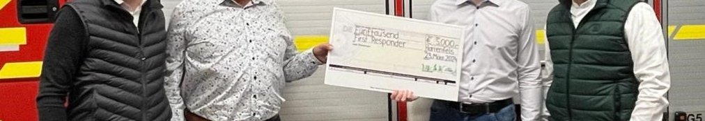 Übergabe eines Schecks an die Feuerwehr Hartenfels Vier Personen stehen vor einem Feuerwehrauto und halten einen Scheck.