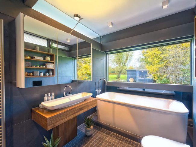 Modernes Bad mit dekorativem Holzwaschtisch Stilvolles Badezimmer mit Badewanne, Waschtisch und Fensterblick