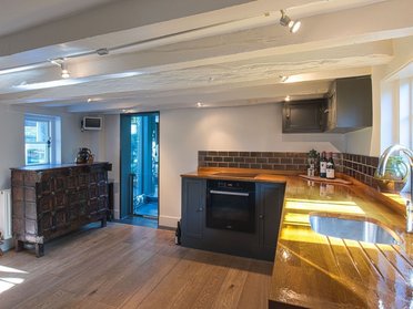 Stilvoller HUF Anbau erweitert den Wohnraum Moderne Küche im harmonischen Anbau mit Holz- und Fliesenelementen