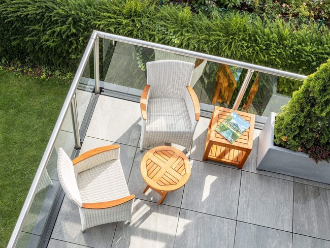 Geräumige Terrasse mit bequemen Stühlen und Tisch, umgeben von Grün