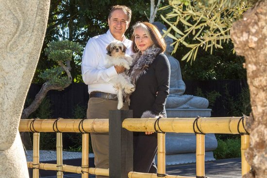 Familie mit Hund vor modernem Haus in naturnaher Umgebung