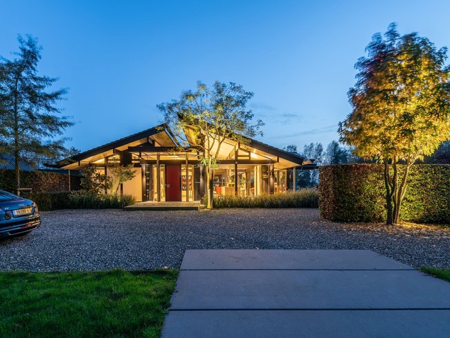 Moderner Bungalow mit organischen Formen in Landschaft Bungalow mit Glasflächen und Gartenbeleuchtung in schöner Umgebung