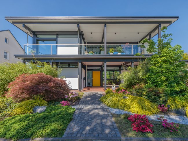 Modernes Designhaus mit Flachdach und Garten Zeitgenössisches Flachdachhaus mit buntem Garten und Terrasse
