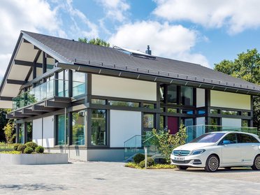 Stylisches Haus mit Glasfront und weißem Auto im Garten