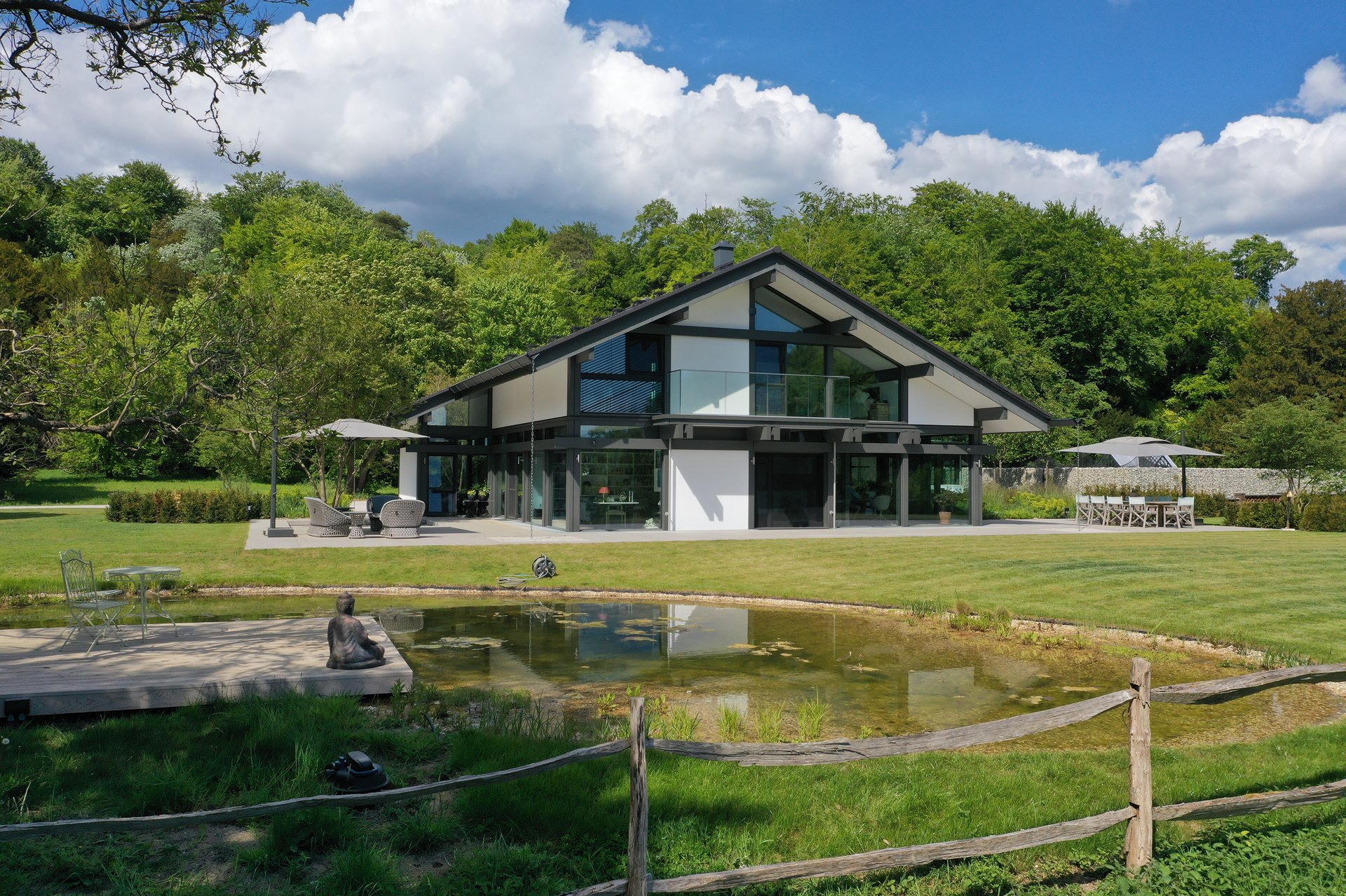 Helles, modernes Haus umgeben von Bäumen und einem Teich
