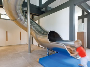 Stylische Innenarchitektur mit runder Stahlrutsche und Sicherheitsmatte