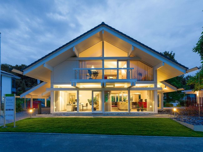Beleuchtetes modernes Haus mit großem Fensterfront bei Abenddämmerung