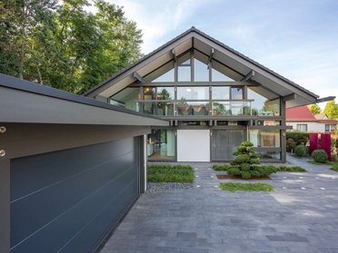 Ein lichtdurchflutetes Holz-Glas-Haus in einer grünen Umgebung