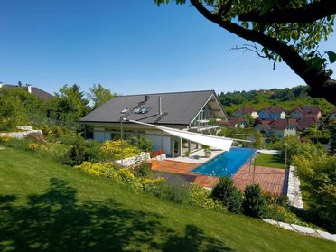 Vielseitiges HUF HAUS mit Glasflächen und Pool in grüner Landschaft