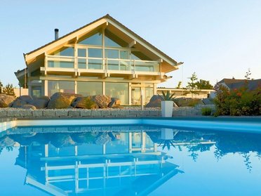 Fachwerkhaus HUF HAUS ART 4 mit Pool Modernes Fachwerkhaus mit Pool und Gartenlandschaft im Hintergrund