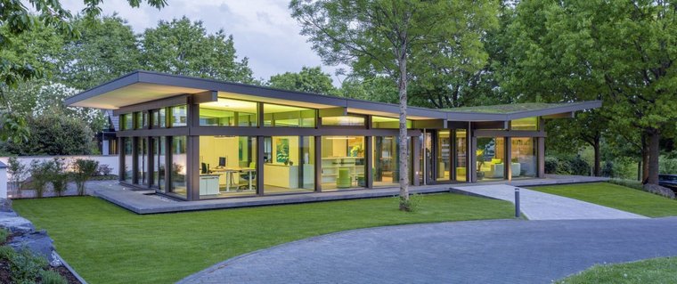 Ein elegantes, modernes Haus mit transparenten Wänden und grünem Garten