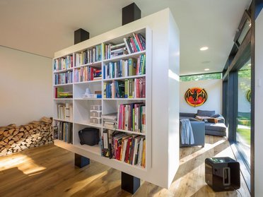Modernes Wohnzimmer mit Bücherregal und Holzstapel im Familienhaus