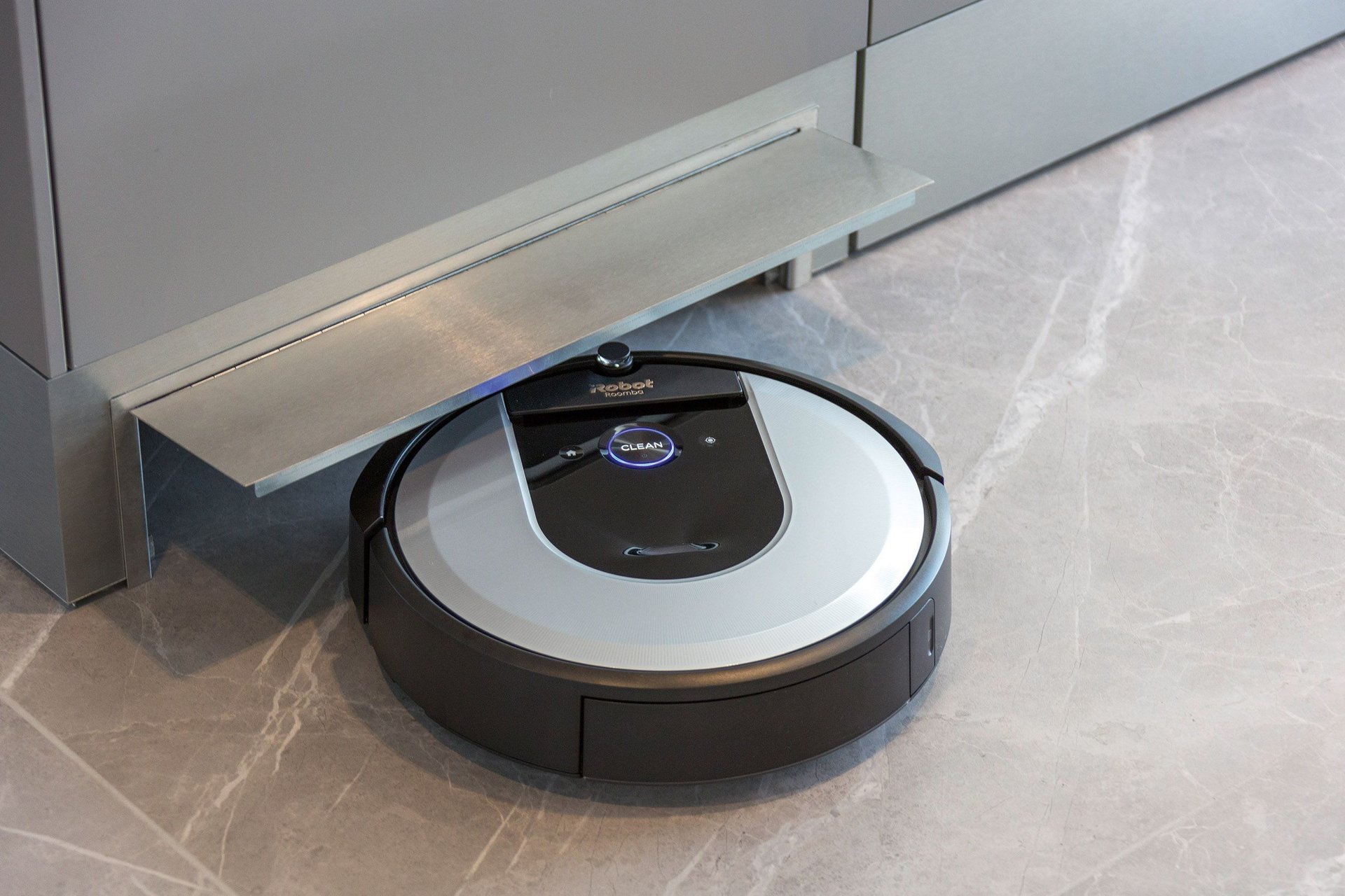Roboterstaubsauger unter der Küchenzeile Ein Roboterstaubsauger ruht unter einer Küchenzeile auf einem modernen Boden