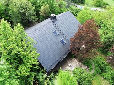 Moderne Dachstruktur umgeben von üppigem Grün Luftaufnahme eines Hauses mit begrünter Umgebung und Bäumen