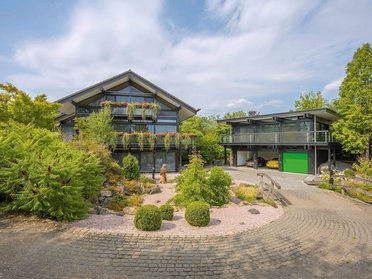 Ansicht eines modernen HUF Hauses mit Garage und Büro, umgeben von Grün