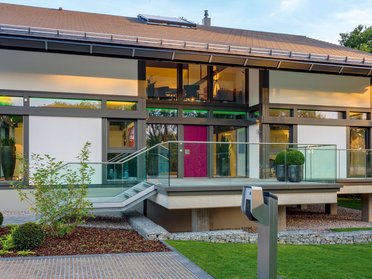 Futuristisches Haus mit großen Fenstern und gepflegtem Garten