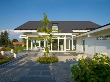 Fachwerkhaus HUF HAUS ART 4 Moderne Architektur mit begrüntem Garten und Terrasse.