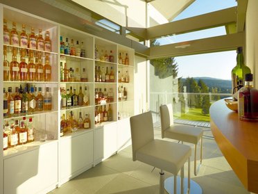 Exklusive Bar in modernem HUF HAUS mit Glasflächen Stylische Bar mit einer Vielzahl von Spirituosen und Blick ins Grüne