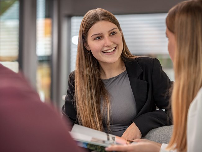 Professionelles Gespräch in moderner Umgebung Junge Frau im Gespräch, lächelnd, im modernen Büro Hintergrund
