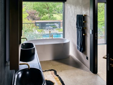Helles Badezimmer mit freistehender Badewanne und Blick ins Grüne