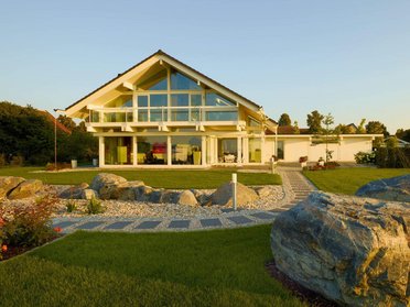 Fachwerkhaus HUF HAUS ART 4 in schöner Landschaft Moderne Architektur eines Fachwerkhauses mit großem Garten und Steinen