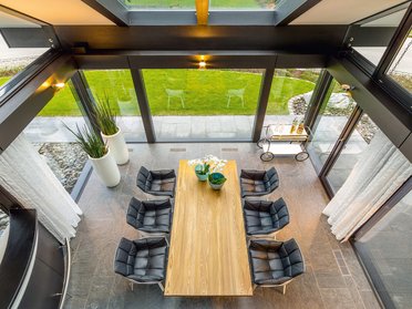 Elegantes modernes Esszimmer mit Glaswänden und gemütlichen Stühlen